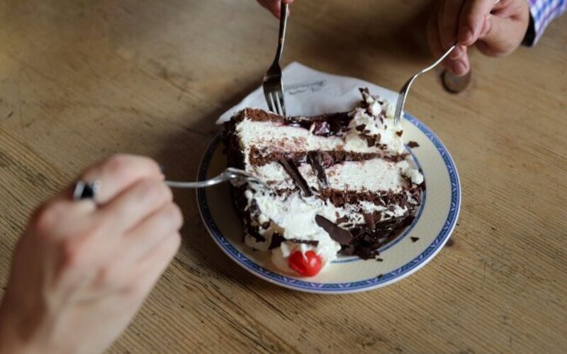 Zwei Personen teilen sich ein Stück Schwarzwälder Kirschtorte und denken dabei nicht an versteckten Alkohol.