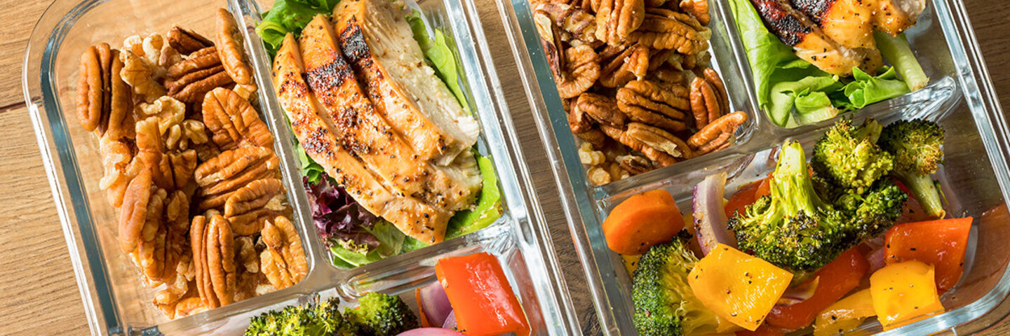 Meal Prep-Dosen gefüllt mit Gemüse, Fleisch und Nüssen.