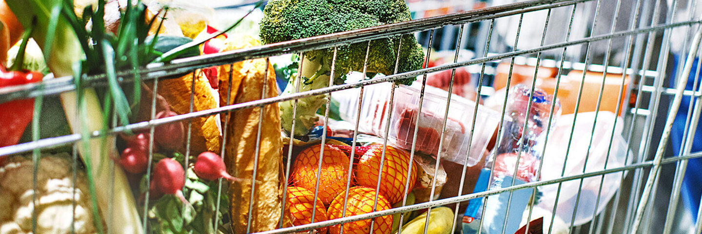 Einkaufswagen in einem Supermarkt, gefüllt mit viel frischem Obst und Gemüse.