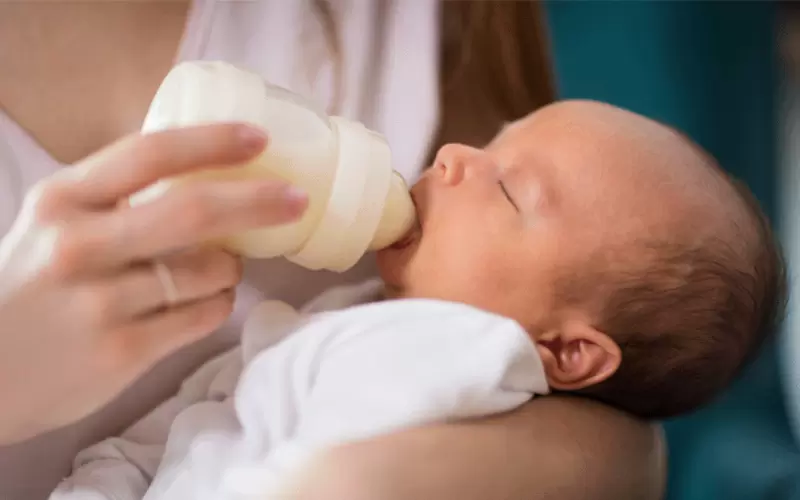 Ein neugeborenes Baby, das mit einer Flasche gefüttert wird.