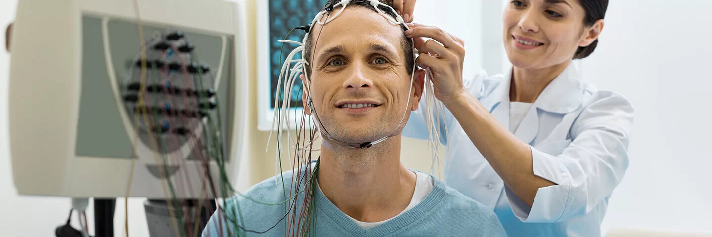 Eine Ärztin des Schlaflabors befestigt Elektroden am Kopf eines Patienten.