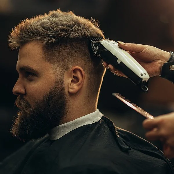 Ein Mann bekommt mit einem Haarschneidegerät den Nacken ausrasiert.