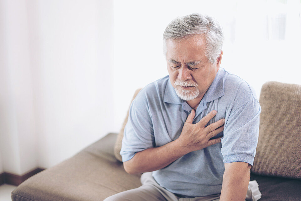 Ein älterer Mann fasst sich mit der Hand an den Brustkorb. Zu den typischen Beschwerden der koronaren Herzkrankheit gehört ein Engegefühl der Brust.