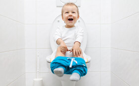 Ein fröhliches Kleinkind sitzt auf der Toilette.