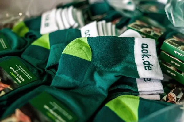 Stapelweise grüne AOK-Socken für die Firmenläufer 2026
