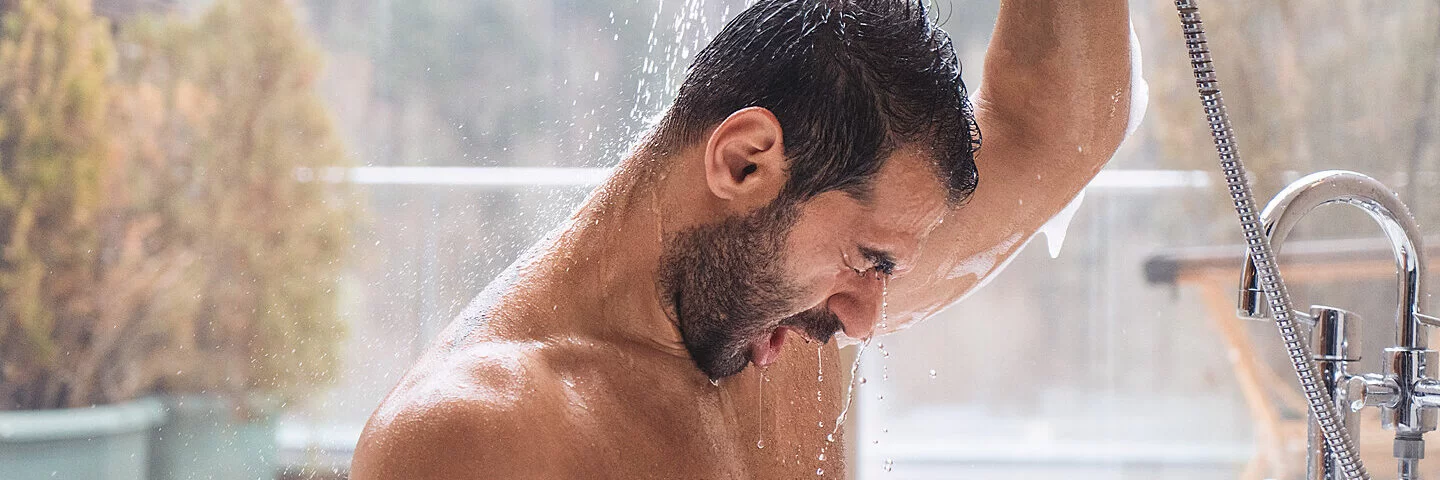 Ein Mann duscht kalt um sein Immunsystem zu stärken.