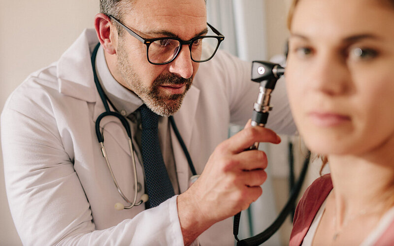 Patientin mit Wasser im Ohr wird von Arzt untersucht.