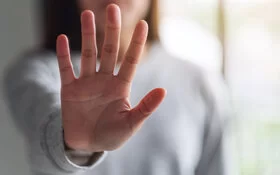 Eine Frau hält ihre ausgestreckte Hand in die Kamera und zeigt Stopp-Handzeichen.
