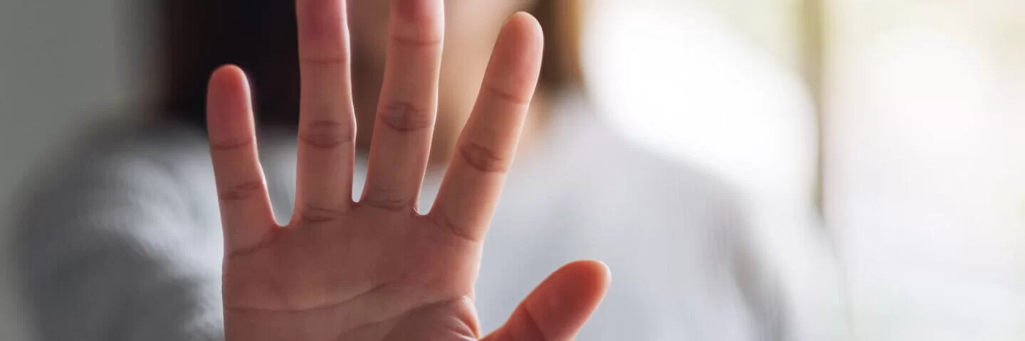 Eine Frau hält ihre ausgestreckte Hand in die Kamera und zeigt Stopp-Handzeichen.