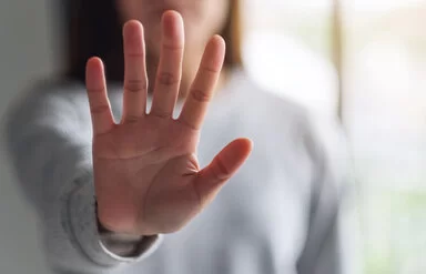 Eine Frau hält ihre ausgestreckte Hand in die Kamera und zeigt Stopp-Handzeichen.