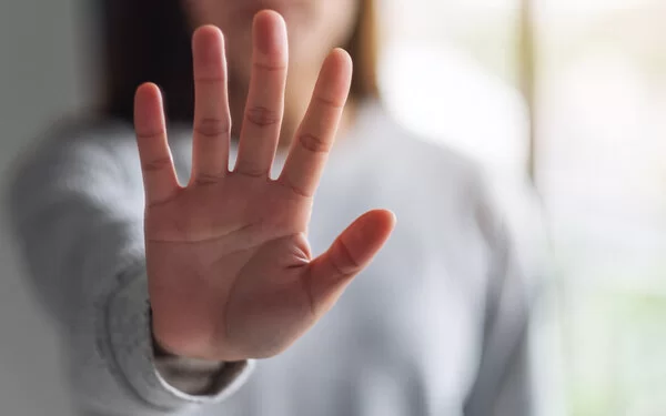 Eine Frau hält ihre ausgestreckte Hand in die Kamera und zeigt Stopp-Handzeichen.