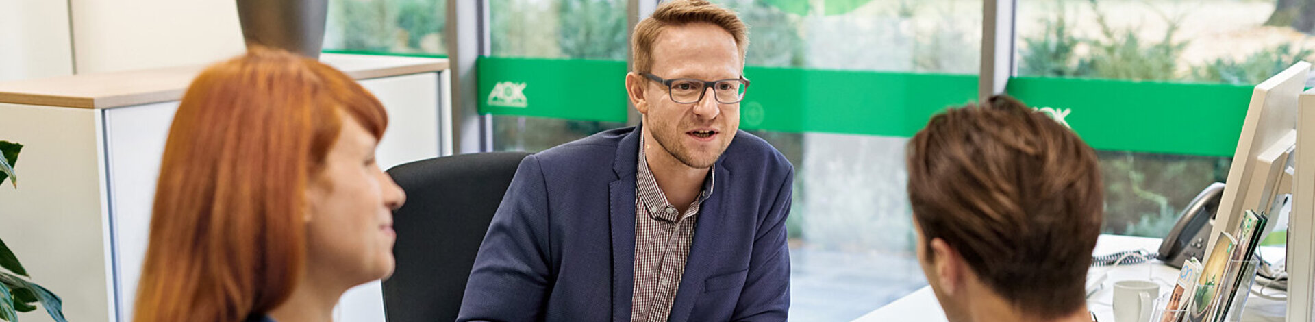 Ein Mitarbeiter der AOK spricht mit Versicherten. Am Flughafen gibt es Ersatz für die Europäische Auslandskrankenkarte.