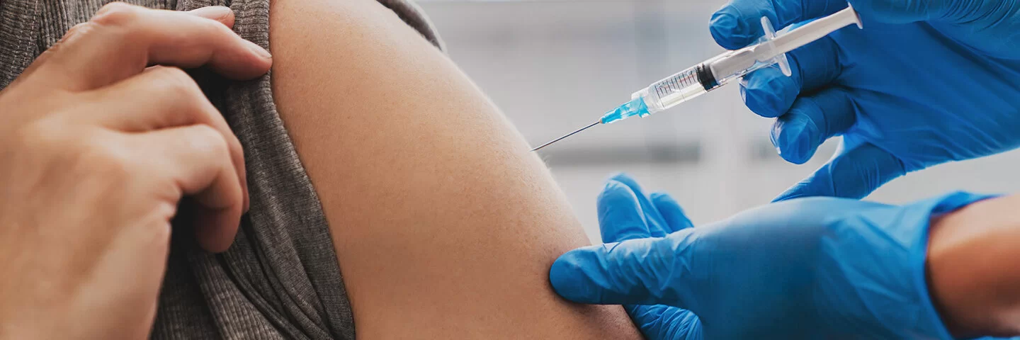 Ein Arzt gibt einem Mann eine Grippeschutzimpfung. Die AOK trägt die Kosten für die Grippeimpfung.