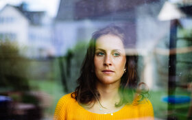 Frau guckt traurig aus dem Fenster und überlegt, wie sie negative Gedanken loswerden kann.