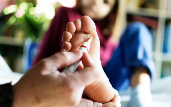 Ein Vater behandelt die Warze am Fuß seiner Tochter.