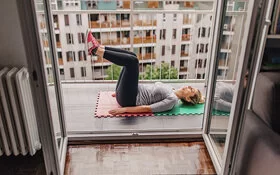 Frau macht Sit-Ups auf dem Balkon.