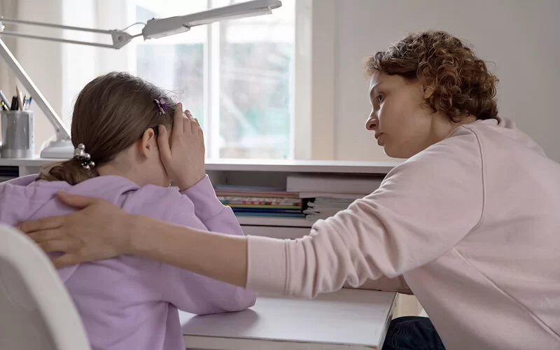 Eine Frau legt ihre Hand um ein Mädchen, um Empathie auszudrücken.