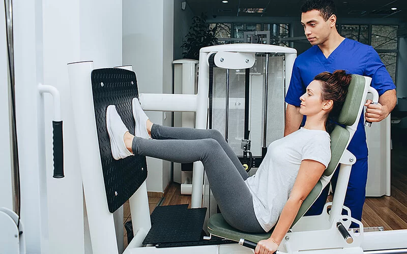 Eine Frau mit Long COVID macht unter Anleitung Sport in einem Rehabilitationszentrum.