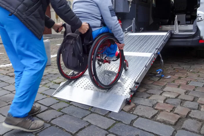 Eine Person im Rollstuhl wird über eine Rampe in einen Van geschoben.