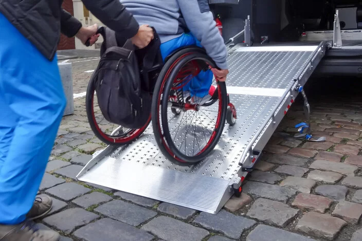 Eine Person im Rollstuhl wird über eine Rampe in einen Van geschoben.