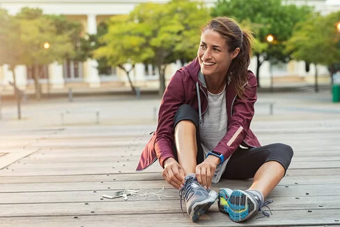 Eine Frau schnürt sich zum Joggen die Laufschuhe zu.