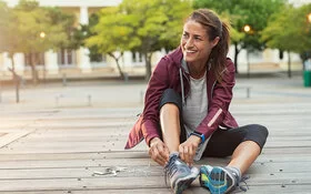 Eine Frau schnürt sich zum Joggen die Laufschuhe zu.