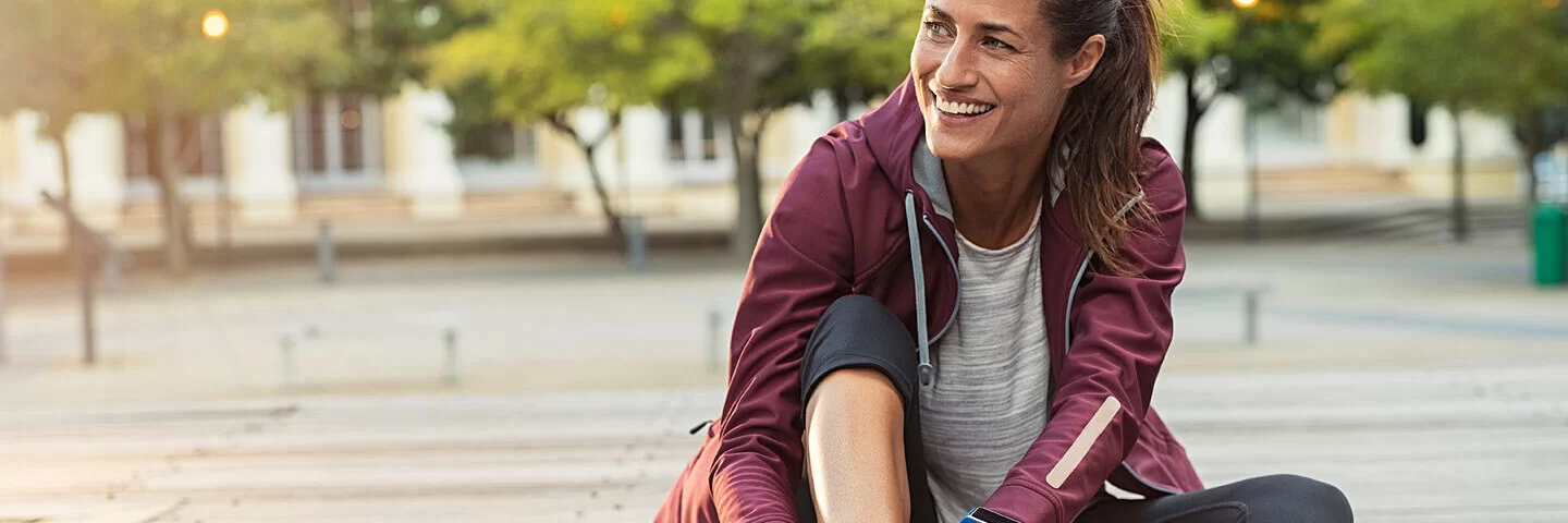 Eine Frau schnürt sich zum Joggen die Laufschuhe zu.