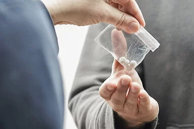 Ein Person übergibt jemandem ein Tütchen mit Legal Highs.
