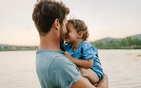 Ein Vater hält sein kleines Kind auf dem Arm. Durch Nähe und Zuwendung können Kinder Resilienz entwickeln und stärken.