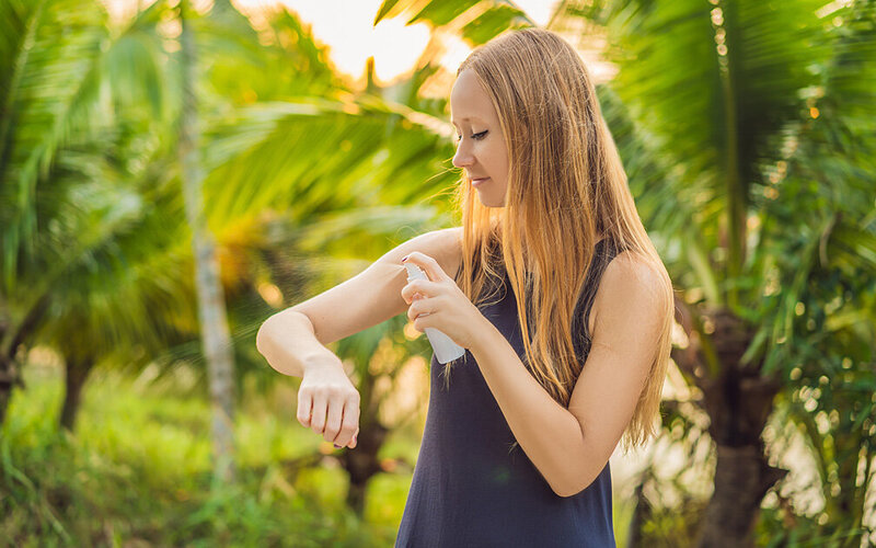 Eine Frau besprüht ihren Arm mit einem Insekten-Repellent.