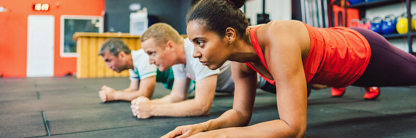 Eine Gruppe macht Planks im Fitnessstudio.