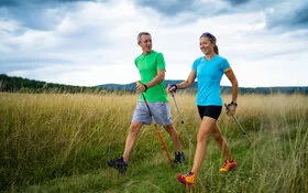 Ein Paar in sportlicher Kleidung betreibt gemeinsam Nordic Walking.