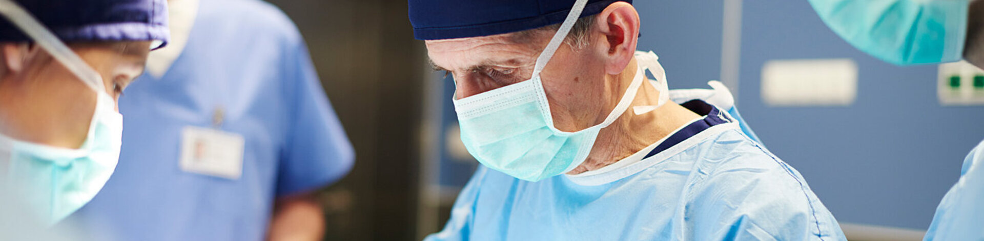 Ein Arzt mit OP-Handschuhen und Maske arbeitet im Operationssaal. Lesen Sie mehr zu Organtransplantationen.