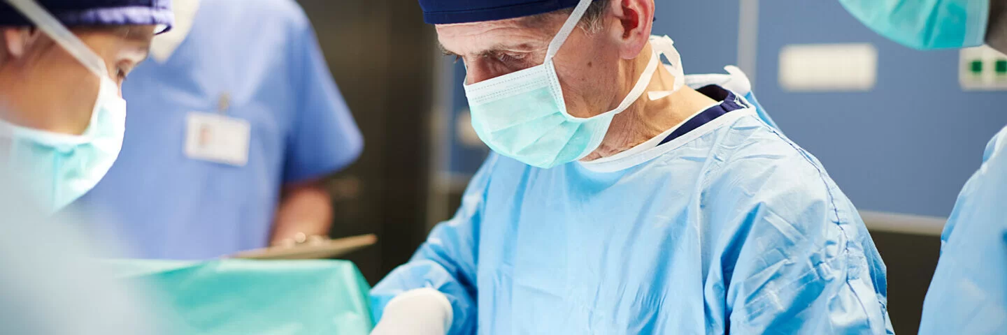 Ein Arzt mit OP-Handschuhen und Maske arbeitet im Operationssaal. Lesen Sie mehr zu Organtransplantationen.