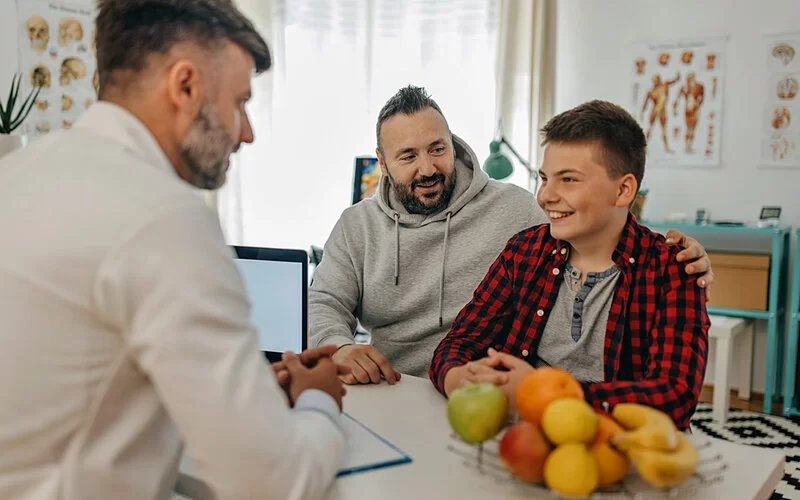 Eine Junge und sein Vater sprechen mit einem Ernährungsberater über gesunde Ernährung.