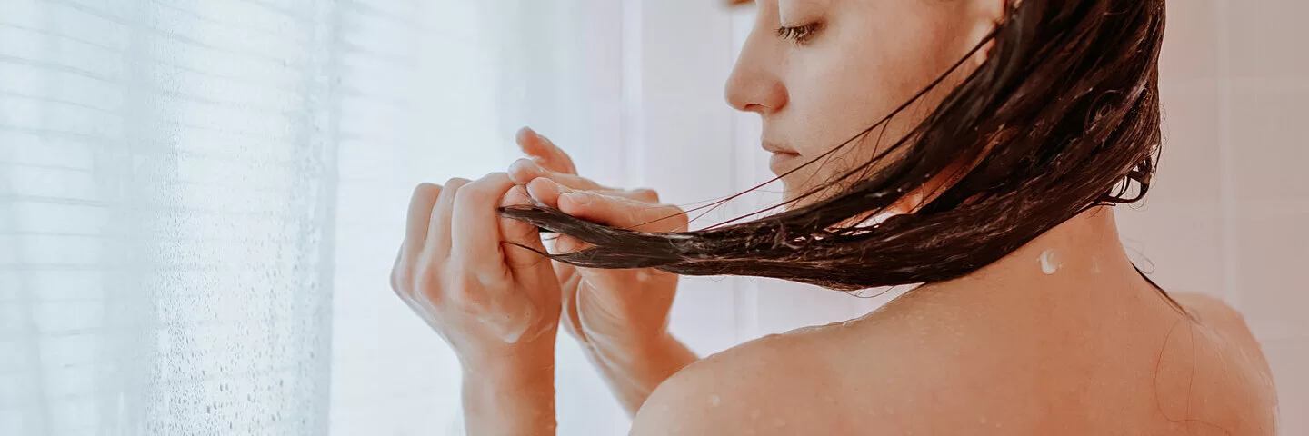 Eine Frau wäscht sich die Haare nur mit Wasser ohne Shampoo.