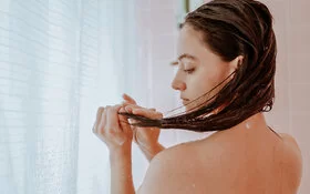 Eine Frau wäscht sich die Haare nur mit Wasser ohne Shampoo.