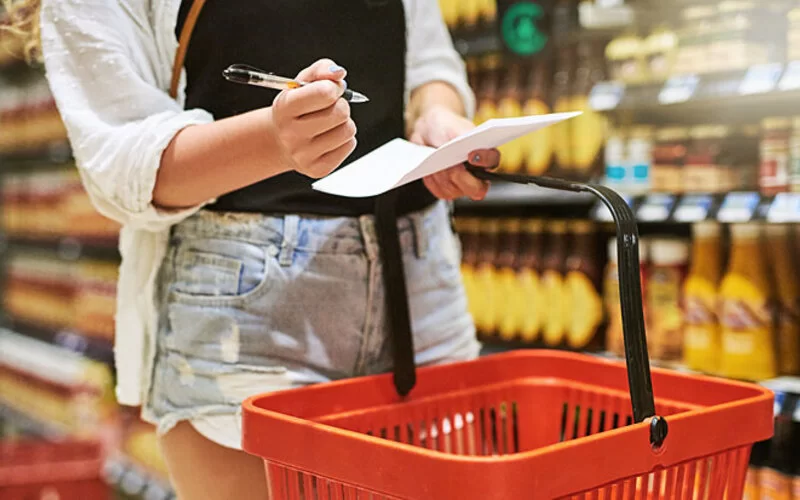 Eine Frau geht im Supermarkt ihren Einkaufszettel durch.