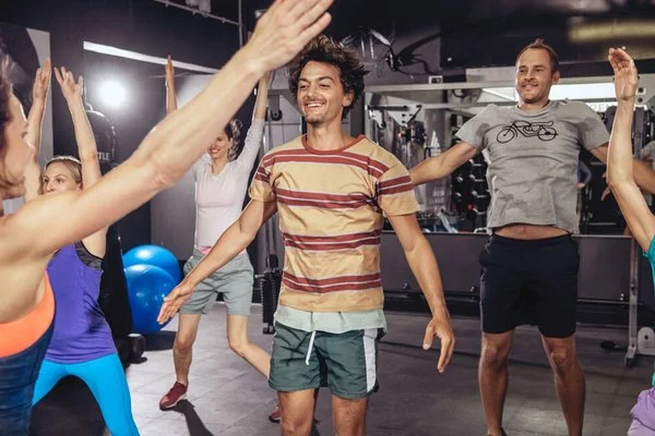 Gruppe von Menschen in Sportkleidung macht im Fitnessstudio Aufwärmübungen
