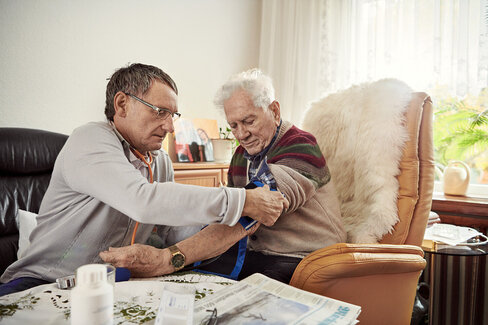 Ein Arzt misst den Blutdruck bei einem Patienten. Blutdruckmessgeräte sind wichtig, um Werte selbst zu überwachen.