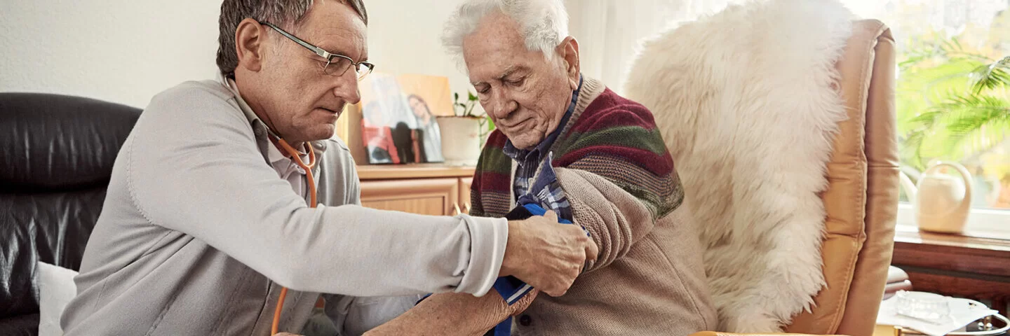 Ein Arzt misst den Blutdruck bei einem Patienten. Blutdruckmessgeräte sind wichtig, um Werte selbst zu überwachen. 