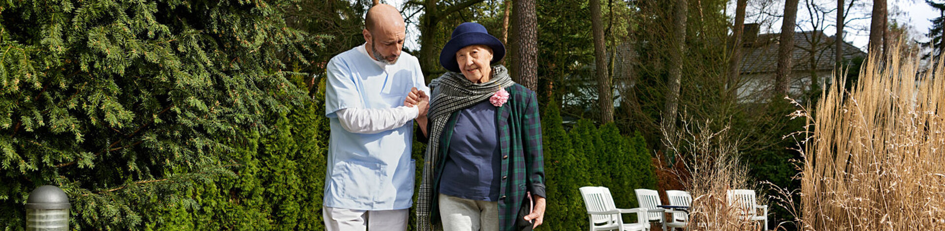 Eine ältere Frau geht mit einem Pfleger spazieren. Sie kann mit einer Betreuungsverfügung bestimmen, wer als rechtlicher Betreuer eingesetzt wird.