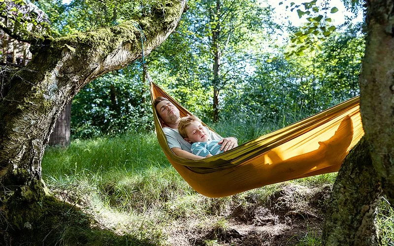 Vater und sein hochsensibles Kind liegen in einer Hängematte.