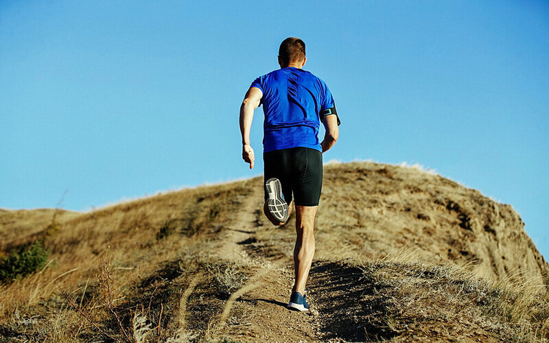 Ein Mann trainiert seine Pace, indem er bergauf läuft.