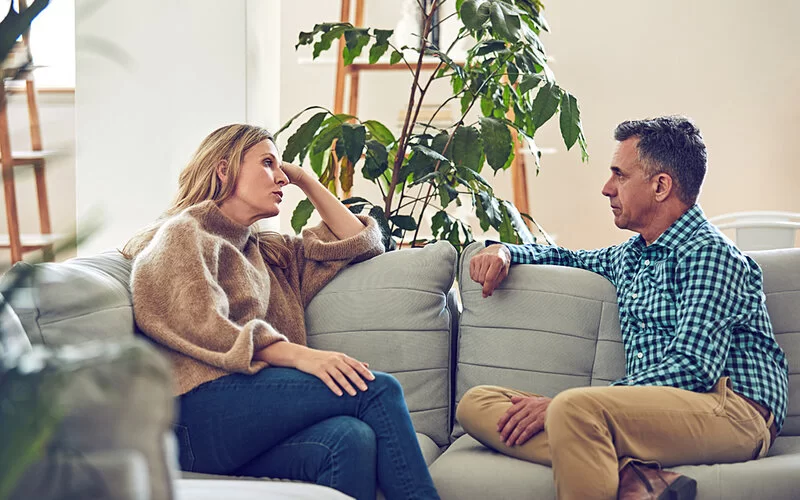 Ein Paar sitzt auf dem Sofa und spricht in einem ruhigen Moment über einen Konflikt.