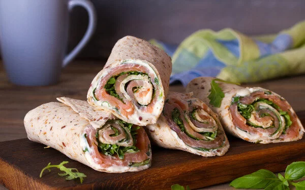 Lachs-Spinat-Wraps auf Holzbrett.