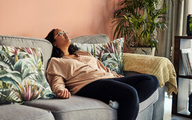 Frau mit Eisenmangelanämie liegt kraftlos auf dem Sofa.
