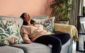 Frau mit Eisenmangelanämie liegt kraftlos auf dem Sofa.