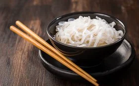 Eine Schüssel mit zubereiteten Konjaknudeln, daneben liegen zwei Essstäbchen.