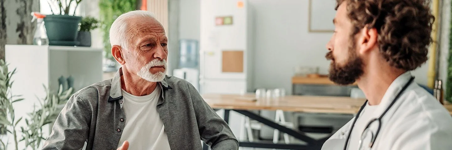 Ein älterer Mann spricht in einer Praxis mit einem Arzt.